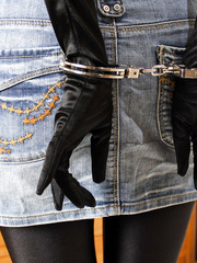 Elena in a denim skirt and handcuffs